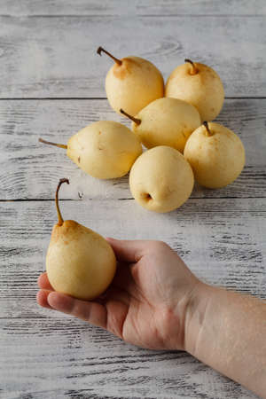 hand with ripe juicy pears on a wooden tableの写真素材
