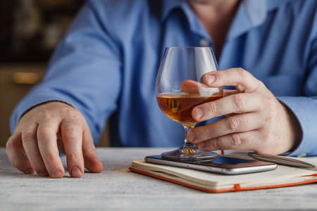cute young man drinks whiskey at tableの写真素材