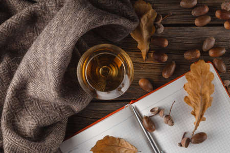 cup of hot dark coffee and scarf with vibrant autumn leaves on rustic woodの写真素材