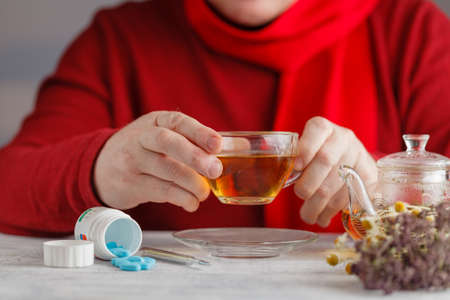 Hands with warm honey tea with herbs.の写真素材