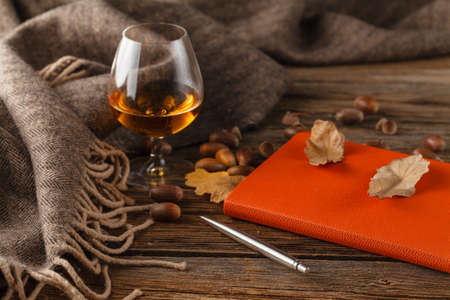 Cup of tea with old book, autumn leaves on wooden tableの写真素材