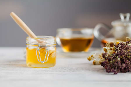 Honey in a glass jar and herbal tea.の写真素材