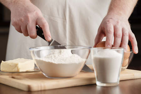 Man in apron making dough for Christmas cookies in kitchen.の写真素材