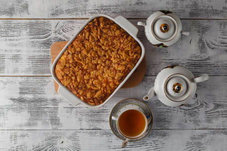 Homemade pie with cheese and apples, cup of tea and fork on white wooden table. Top view.の写真素材