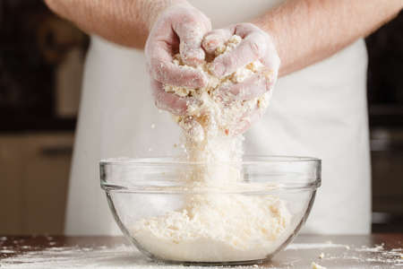 Man in apron making dough for Christmas cookies in kitchen.