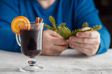 Mulled wine with addition of an orange, honey, cinnamon, a carnation and an anise, man's hands hold with mulled wineの写真素材