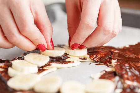 Hands with Chocolate cake with banana on dark background, selective focus.の写真素材