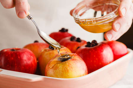 Man with Spoon pouring honey on apple. making baked apple.の写真素材