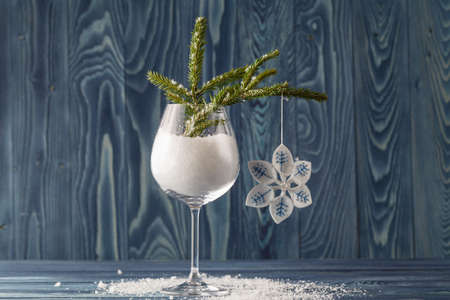 Snow in wine glass, tree branches and Christmas balls on old wooden background, selective focusの写真素材