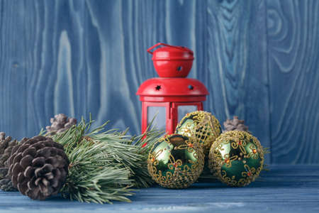 Red Christmas lantern and balls on a wooden table. Christmas tree and lights at the backgroundの写真素材