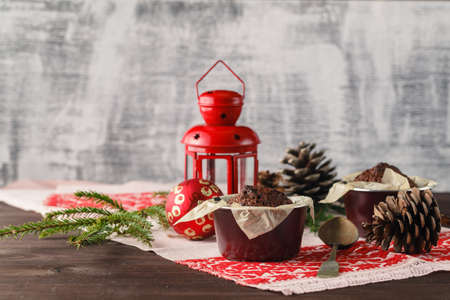 Chocolate cake and little cupcakes with holiday decorations on rustic tableの写真素材