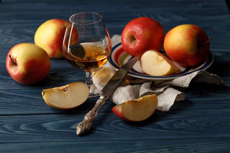 Apple cider in wine glass with cinnamon sticks and fresh apples on wooden backgroundの写真素材