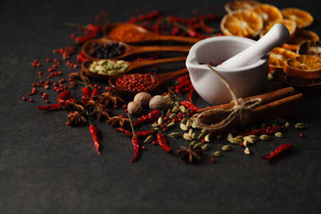 Spices in wooden spoon on dark stone surfaceの写真素材