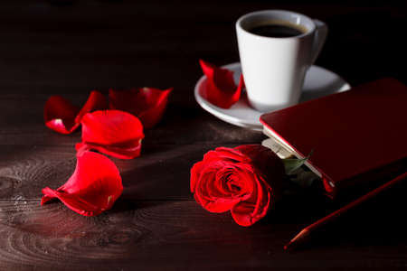 early morning in cafe. Red rose in notebook and coffeeの写真素材