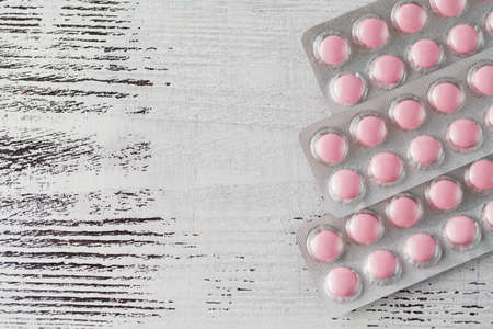 Various pills and capsules in blister packagings piled up on a tableの写真素材