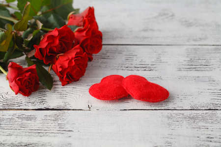 Few red roses on white table with soft felt heartの写真素材
