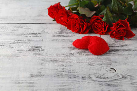 Few red roses on white table with soft felt heartの写真素材