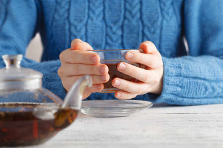 Woman hold glass cup of tea in handsの写真素材