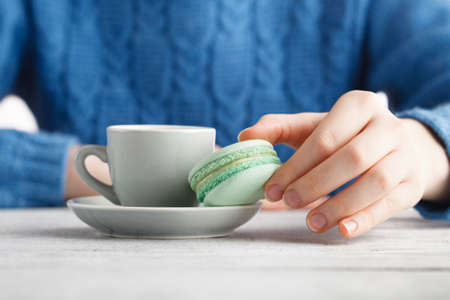 Girl drink coffee and hold macaroonの写真素材