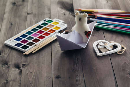 Paper boat and soft toy on wooden tableの写真素材