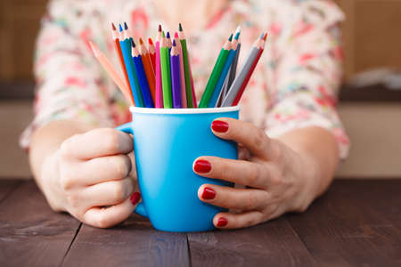 Woman hold mug with many color pencilの写真素材