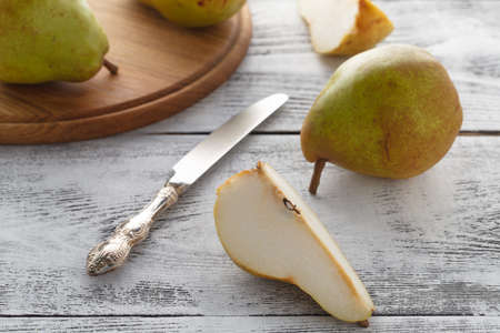 fresh sliced pears on wooden table with knifeの写真素材