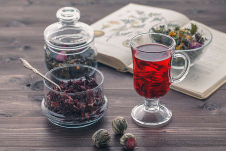 Herbal tea mixture in a glass bowl and medicine bookの写真素材
