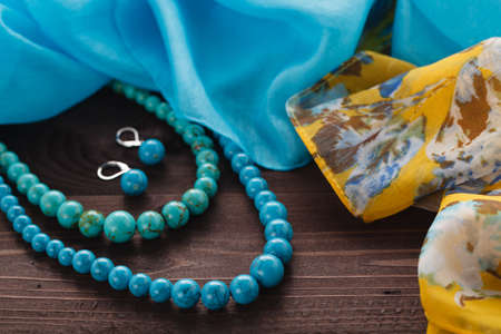 turquoise handmade bijouterie lay on table with silk shawlの写真素材