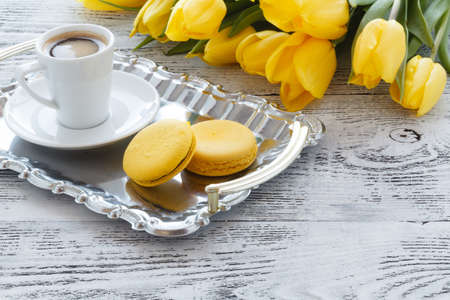 Breakfast concept. Bunch of yellow tulips on table with coffeeの写真素材