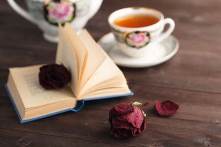Dried rose laying over an open book on wooden tableの写真素材