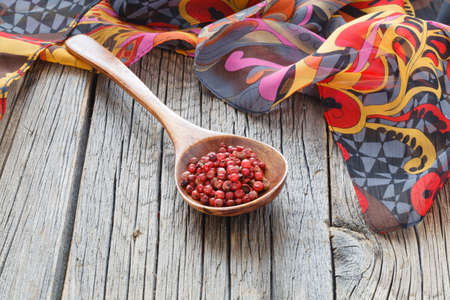 Pepper in a wooden spoon on wooden rustic tableの写真素材