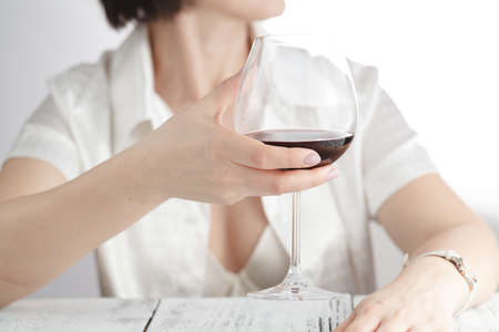 Female drink wine at office. Work time end
