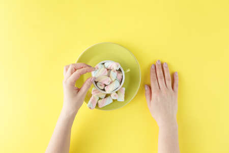 Female hands with Twisted colored marshmallow in cupの写真素材