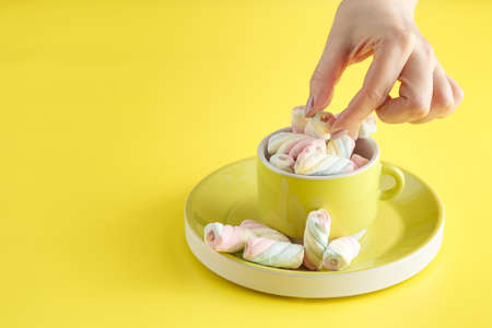 hand holding bowl of sweet Marshmallow pastel isolated on yellow background.の写真素材