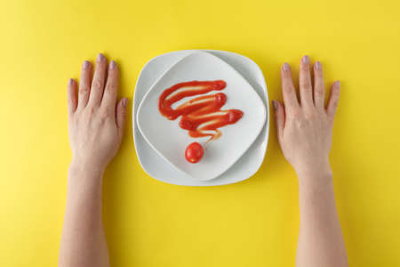 flat lay of ketchup line on white dish on yellow  background