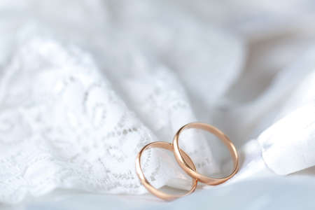 Wedding dress lace closeup with golden ringsの写真素材