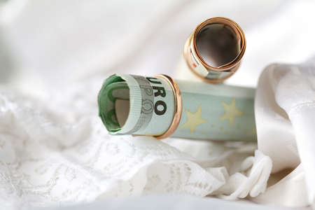Wedding rings and money on a white bridal lingery backgroundの写真素材