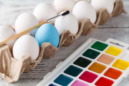 Easter, holidays, tradition concept - close up of coloring easter eggs with colors and brush
