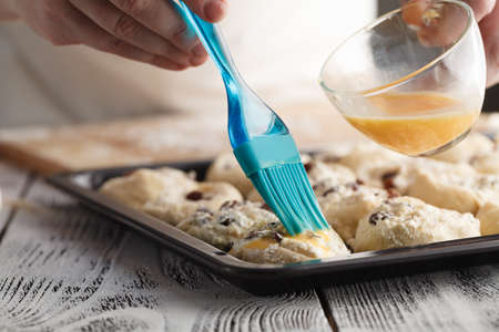 Raw sweet yeast dough on a baking sheet, filling buns raisin. Preparation for baking. The concept of chefs and baking.の写真素材