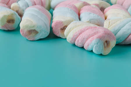 Rainbow color of spiral marshmallows on aquamarine and blue backgroundの写真素材
