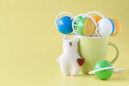 Baby toy bear with baby rattle on a yellow backgroundの写真素材