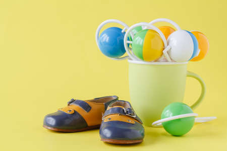 Baby rattle and booties on yellow backgroundの写真素材