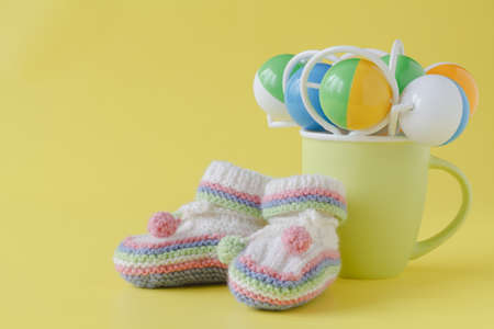 Baby rattle and booties on yellow backgroundの写真素材
