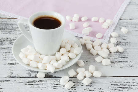coffee cup with hot drink and tasty marshmallow, roasted beans on wooden tableの写真素材