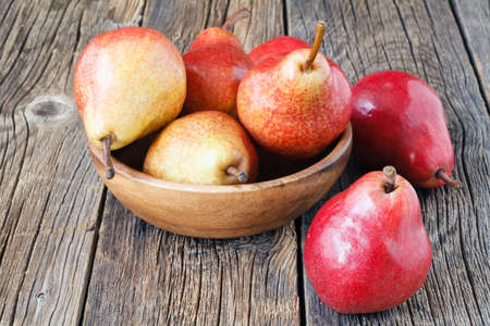 Fresh, sweet pears in a wooden bowl on the tableの写真素材