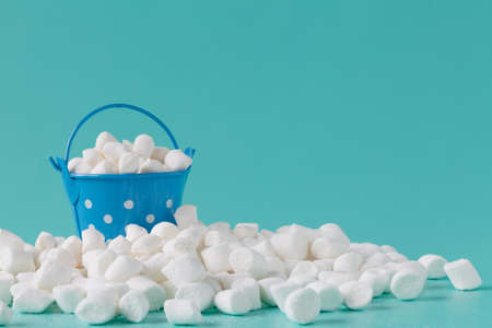 pile of small puffy marshmallows on aquamarine background close upの写真素材