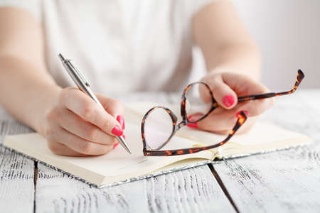 Woman writing in notepad placed on bright desktop. Education conceptの写真素材