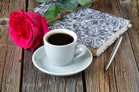 book with beautiful roses and cup of coffee on wooden table close upの写真素材