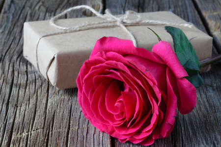 Single fresh pink rose symbolic of love and romance on a rustic wooden table for a sweetheart on Valentines Day, Mothers Day or anniversaryの写真素材