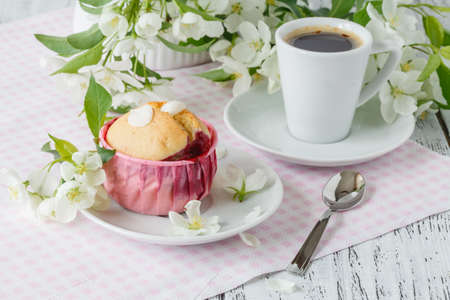 spring Breakfast. muffin and cup of tea on a table, the branch blossoming in the small white flowersの写真素材
